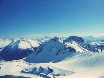 Scenic view of ski slope and snow covered mountains