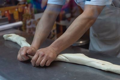 Midsection of chef kneading dough in kitchen