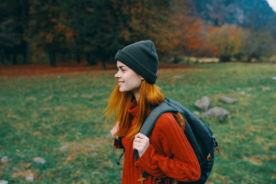 Young woman looking away while standing on land during autumn
