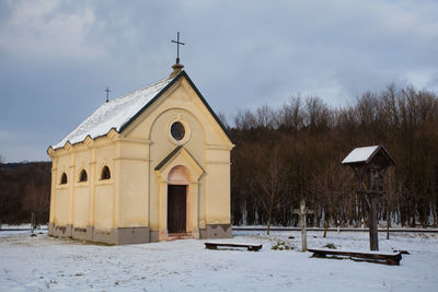 Church by building against sky during winter