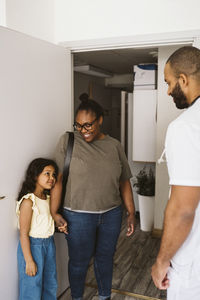 Girl looking at male pediatrician while standing by mother at medical clinic doorway