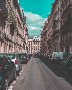 Cars on street in city against sky