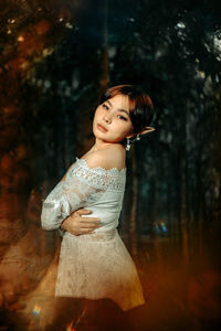 Portrait of woman standing against tree