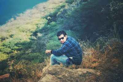 Portrait of man sitting on rock in forest