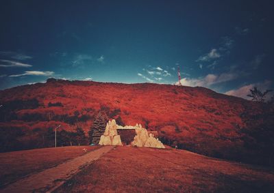 Scenic view of land by mountain against sky