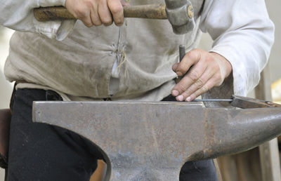 Midsection of man working on metal in workshop