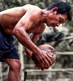 Close-up of shirtless man working outdoors