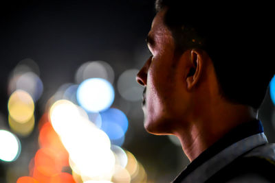 Close-up of man against illuminated lights at night