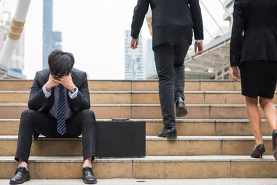 Businessman with headache sitting on steps in city