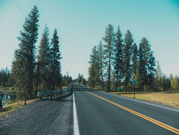 Road amidst trees against clear sky