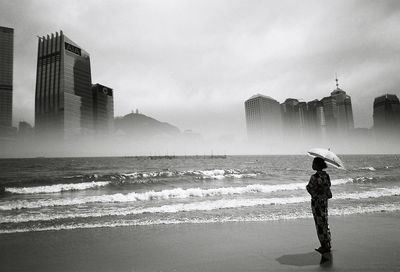 Woman standing on beach against built structures