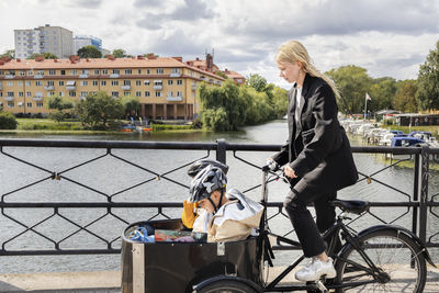 Mother riding bicycle with children in carriage