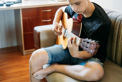 Guitar lessons for beginners. caucasian teenager playing guitar, having online guitar lessons