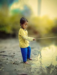 Cute boy looking away while standing in water
