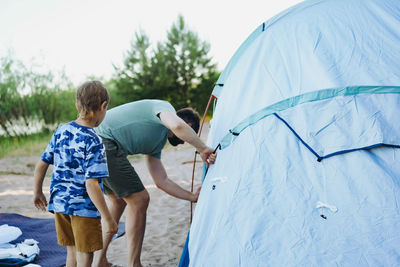 Cute little caucasian boy helping to put up a tent. family camping concept