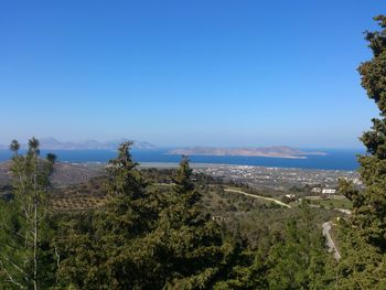 Scenic view of landscape and sea against clear blue sky