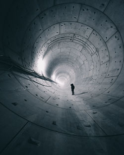 Rear view of silhouette man walking in tunnel