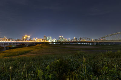 Illuminated bridge over river in city at night