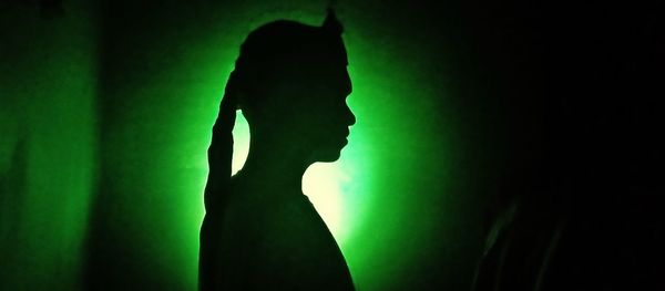 Side view of silhouette woman standing in dark room