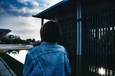 Rear view of man standing by railing against sky