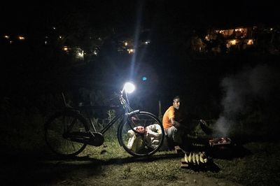 People sitting on illuminated street at night