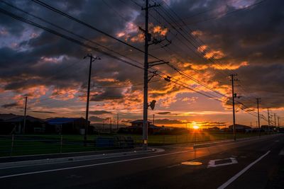 Cars on road against dramatic sky during sunset