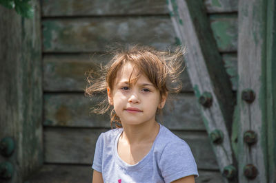 Portrait of girl against wooden play equipment