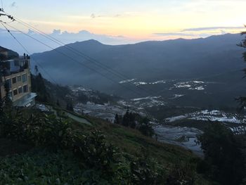 Scenic view of buildings and mountains against sky during sunset