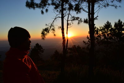 Silhouette man looking at sunset