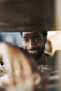Smiling male baker arranging fresh cinnamon buns on cooling rack while working at bakery