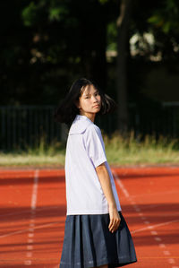 Girl looking away while standing against blurred background