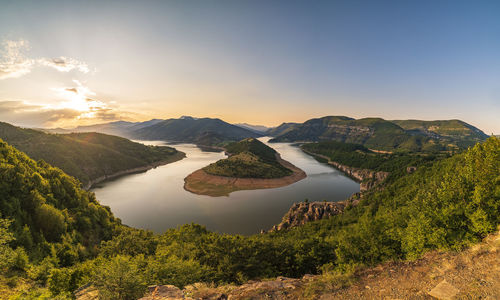 High angle view of river amidst lands against sky during sunset