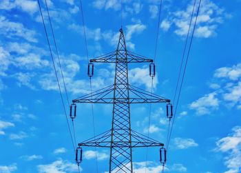 Low angle view of electricity pylon against blue sky