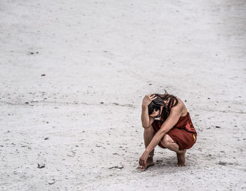 Close up of a woman walking on the sand viewed from behind, low angle