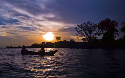 Silhouettes of fishermen on lake victoria at sunset