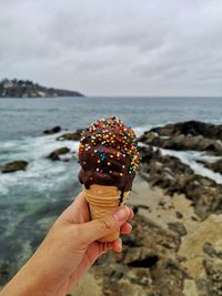 Cropped hand of person holding icecream at beach