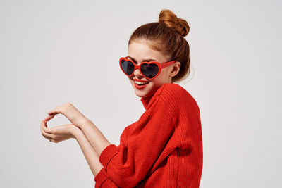 Young woman wearing sunglasses standing against white background
