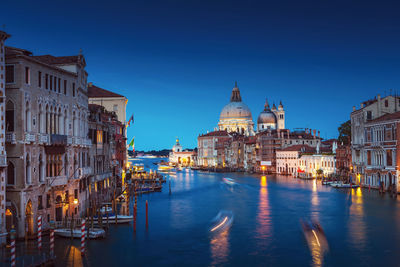 Blurred motion of boats in canal by santa maria della salute against sky at dusk