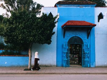 Rear view of woman walking by building