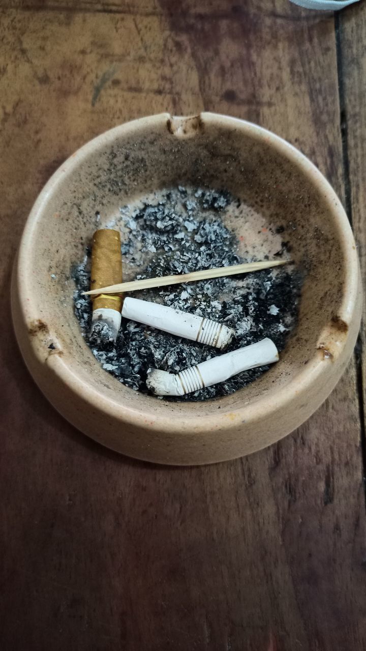 HIGH ANGLE VIEW OF CIGARETTE IN CONTAINER ON TABLE WITH TEXT