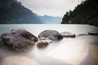 Rocks by river against sky