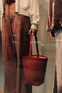 Details of a white knitted sweater, brown trousers and a leather bag. casual women's fashion cloth