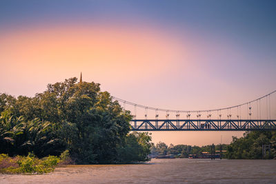 Bridge over river against sky during sunset