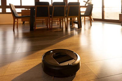 Robotic vacuum cleaner on laminate wood floor in dinning room under sunlight