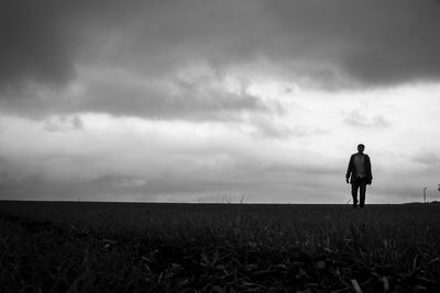 Rear view of man standing on field against sky