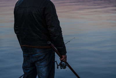 Rear view of man standing by lake