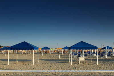 Stilt houses on beach against clear blue sky