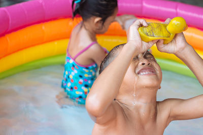 High angle view of siblings enjoying in wading pool