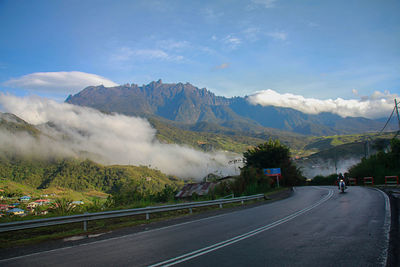 Road by mountains against sky