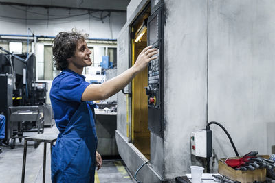 Smiling technician operating cnc machine in metal industry